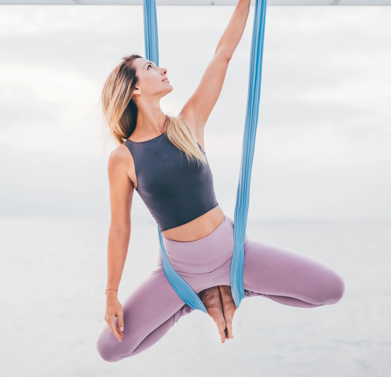 woman performing aerial yoga on sky blue hammock orbsoul